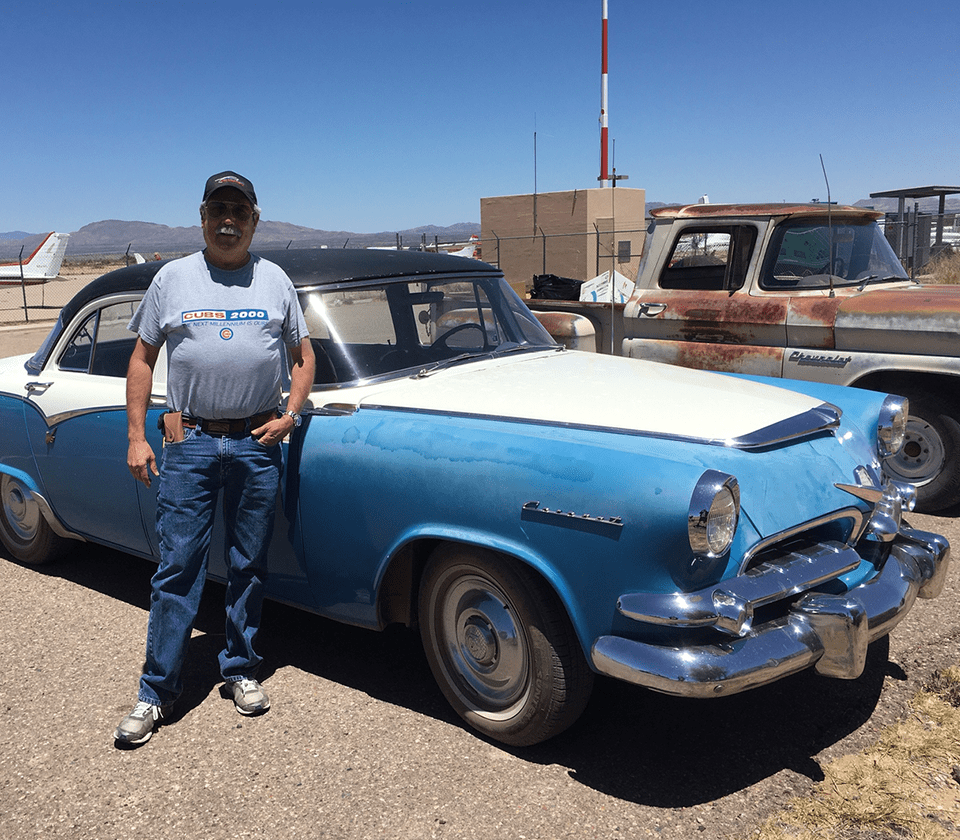 A man standing next to an old car.